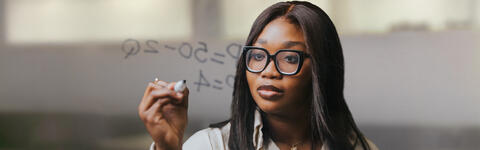 Imperial MSc Innovation, Entrepreneurship & Management student on campus in London writing an equation on a clear board